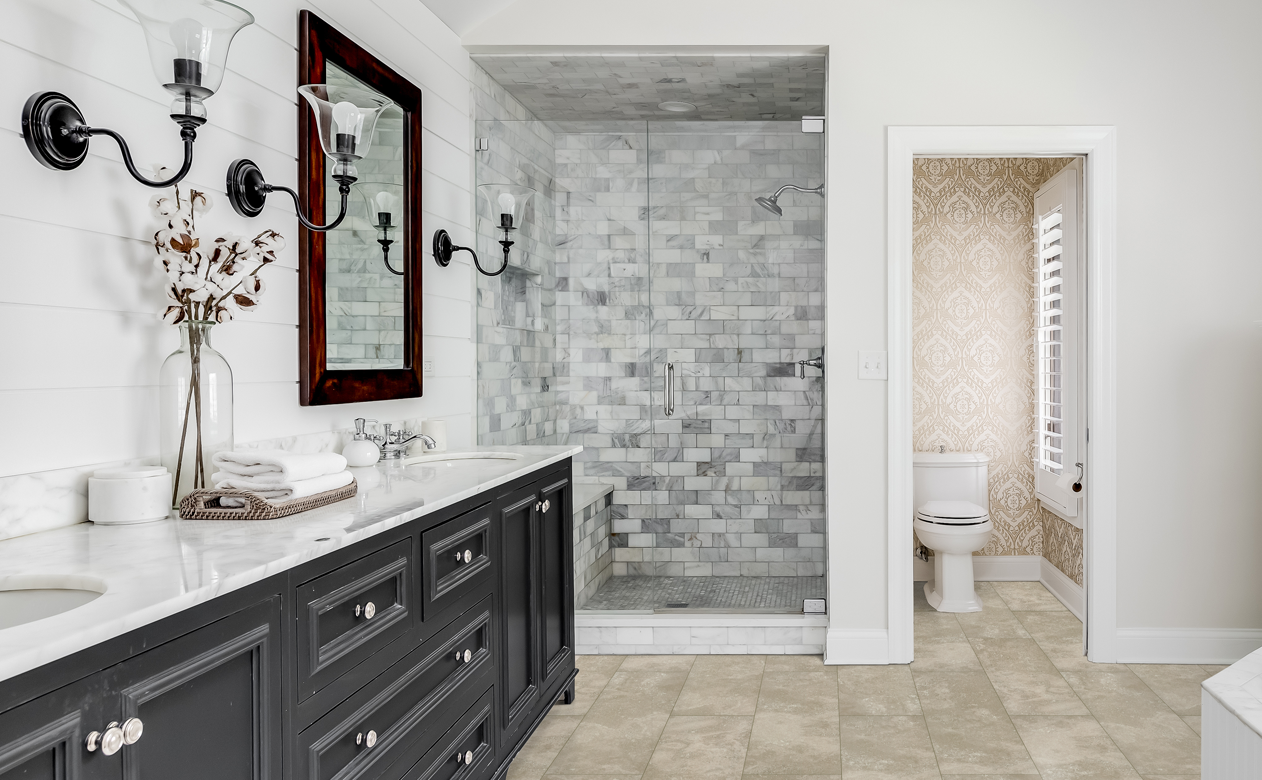 Walk in shower with marble subway tile shower surround in large bathroom with neutral floors and brown vanity